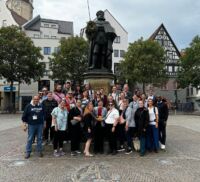 NAFAns standing in front of statue in square.