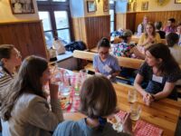 NAFAns seated around table eating food and conversing.